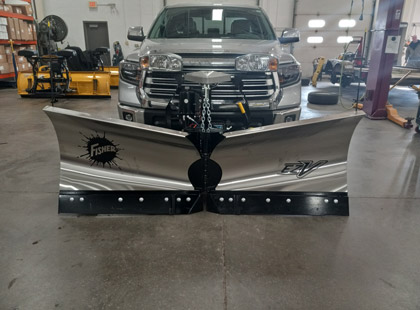 A front view of a silver truck with a Fisher EZ-V v-plow attached